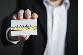 Image of a man holding a business card that displays the DAZA Development logo. 